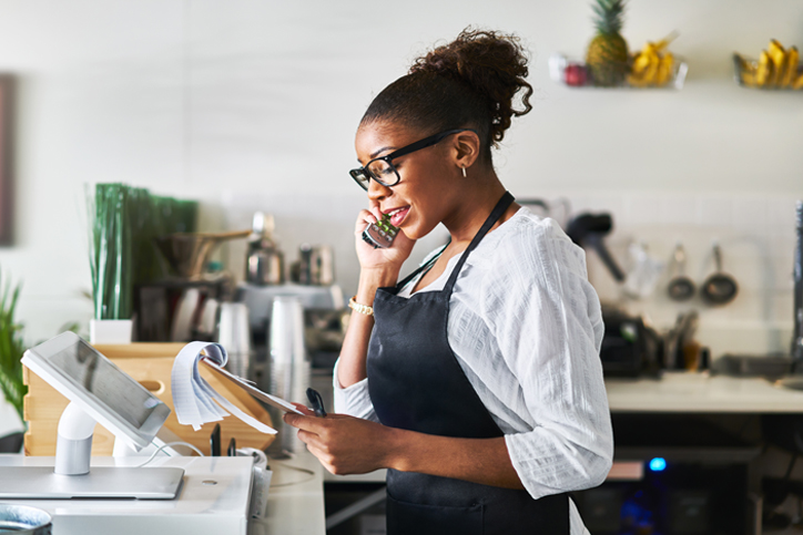 Woman in retail store on phone looking at notebook